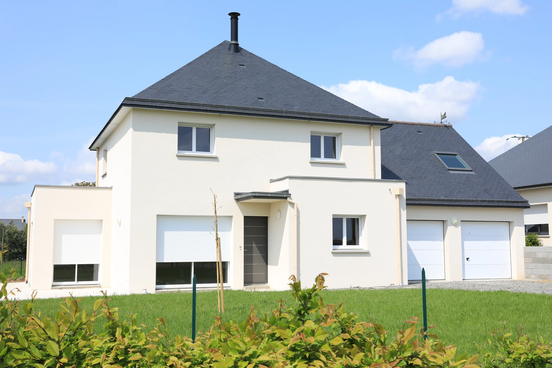 Maison individuelle contemporaine à étage avec façade enduit blanc, toiture ardoise grise et cheminée