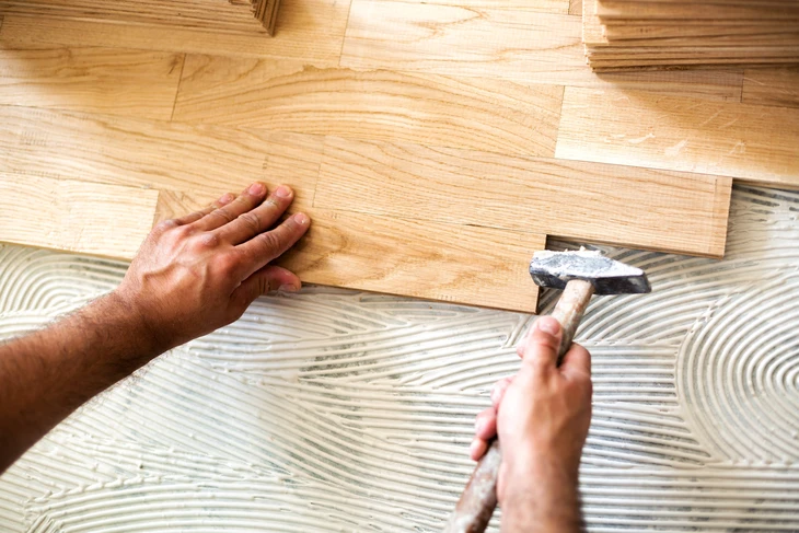 Plancher en bois massif aux tons chauds miel et brun, assemblage de lames rectangulaires de largeurs variables disposées en quinconce